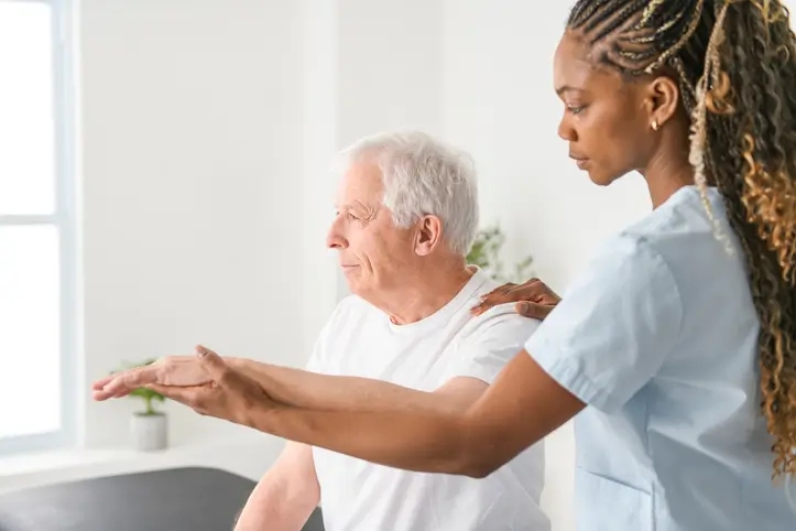 A woman therapist assists an older man with his arm during physical therapy at a skilled nursing facility in Shreveport, LA