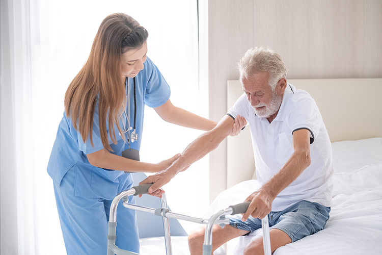 A hospice care nurse in Shreveport helps a senior man get up from his bed