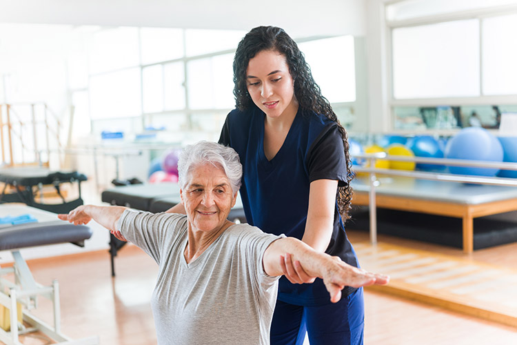 A woman helps an older woman stretch, focusing on stroke recovery care in Shreveport, LA